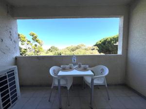 ein weißer Tisch und Stühle in einem Raum mit einem Fenster in der Unterkunft Joli studio avec balcon vue mer à St Florent 140 in Saint-Florent