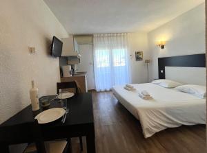 ein Hotelzimmer mit einem Bett und einem Schreibtisch und einem Zimmer in der Unterkunft Joli studio avec balcon vue mer à St Florent 140 in Saint-Florent