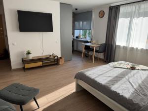 a bedroom with a bed and a tv on the wall at Center Studio type Apartment in Jelgava