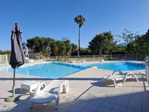 ein Swimmingpool mit zwei Stühlen und einem Sonnenschirm in der Unterkunft Joli studio avec balcon vue mer à St Florent 140 in Saint-Florent + 7 Fotos