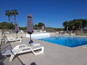 einen Pool mit Stühlen und Sonnenschirmen neben einem Pool in der Unterkunft Joli studio avec balcon vue mer à St Florent 140 in Saint-Florent