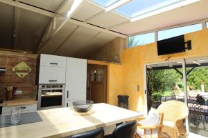 a kitchen with a table with chairs and a television at Au Domaine Paisible - Appartement de charme avec piscine au cœur des Vosges in Hadol