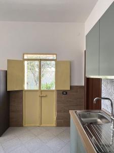 a kitchen with a yellow door and a sink at Casa di Vita in Marina di Lizzano