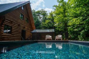 a pool with two chairs next to a house at The ANIMAL - PARTY TIME - POOL SPA AND MOUNTAIN in Saint-Philémon