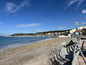 una spiaggia con panchine e l'oceano in una giornata di sole di Appartement 3 pièces climatisé avec parking - Saint-Cyr-sur-Mer - FR-1-845-3 a Saint-Cyr-sur-Mer