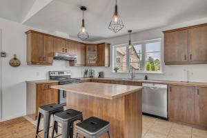 a kitchen with wooden cabinets and a counter with stools at Initial - Jumeau 33 - MSA in Saint-Férréol-les-Neiges +42 photos
