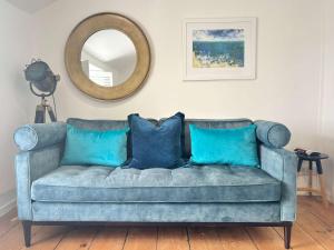 a blue couch in a living room with a mirror at Quaint Cosy Cottage Mousehole in Mousehole