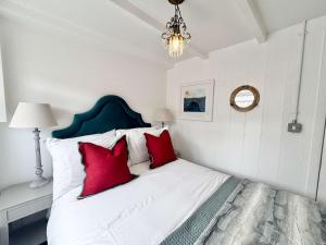 a bedroom with a bed with red pillows and a chandelier at Quaint Cosy Cottage Mousehole in Mousehole