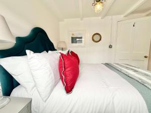 a bedroom with a white bed with red pillows at Quaint Cosy Cottage Mousehole in Mousehole