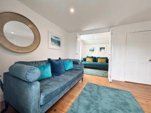 a living room with a blue couch and a mirror at Quaint Cosy Cottage Mousehole in Mousehole +30 photos