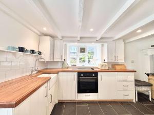 a kitchen with white cabinets and a window at Quaint Cosy Cottage Mousehole in Mousehole