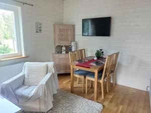 a dining room with a table and chairs and a television at Charming cottage on Kvegero in Gnesta
