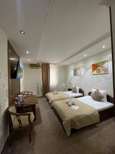 a hotel room with two beds and a desk at Nur M Hotel in Yakkasaray