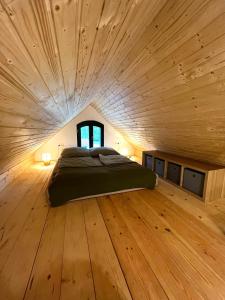 a large bed in a room with a wooden ceiling at Vályog Kuckó in Somogyszentpál