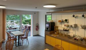 a kitchen with a counter and a table and chairs at Brit Hotel Essentiel Millau in Millau