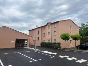 a parking lot in front of a large building at Brit Hotel Essentiel Millau in Millau