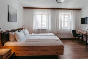 a bedroom with a bed and a desk and windows at Hotel Gasthof Kern in Halfing