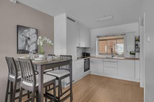 eine Küche mit einem Tisch und Stühlen sowie eine Küche mit weißen Schränken in der Unterkunft Northstay - Tromsø Outlook, Amazing City & Mountain Views in Tromsø + 16 Fotos