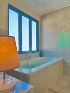 a bathroom with a bath tub with a window at Tropical Lux 5BR Villa Panoramic Isola Bandung in Bandung +44 photos