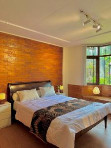 a bedroom with a large bed with a brick wall at Tropical Lux 5BR Villa Panoramic Isola Bandung in Bandung