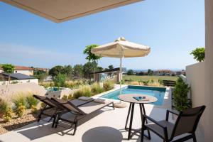 a patio with a table and chairs and an umbrella at Anore Luxury Suites in Nikiti