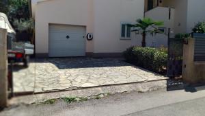 a house with a garage door and a driveway at LAVANDA Apartman in Malinska