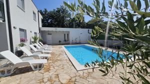 a pool with white lounge chairs next to a building at Villa Sveta Obitelj in Međugorje