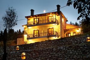 a large stone house with lights on a stone wall at Kaloneri Rooms in Kaloneri