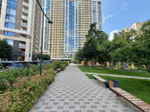 a walkway in a park with benches and buildings at PREMIUM apartments ЖК Автограф, Институт сердца, МВЦ, Центр серця, Братиславская, Юность, Черниговская, Левобережная, Дарница in Kyiv