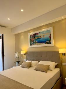a bedroom with a white bed with a painting on the wall at Hotel Kali Sorrento in Sorrento