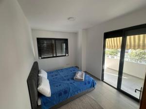 a bedroom with a blue bed and a window at Seaside 2-br flat with terrace in Golem