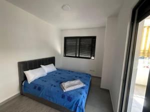 a bedroom with a bed with blue sheets and a window at Seaside 2-br flat with terrace in Golem