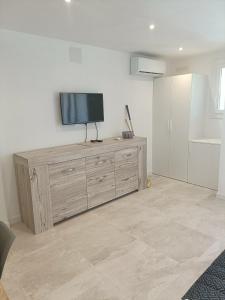 een flatscreen-tv op een houten dressoir bij LES CORAUX AGAY in Agay - Saint Raphael
