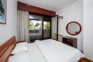 ein Schlafzimmer mit einem Bett, einem Spiegel und einem Fenster in der Unterkunft Grand Hotel in Cetinje