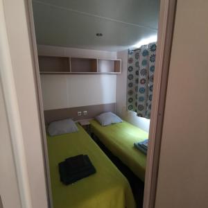 two beds in a small room with green sheets at Mobilhome 6P 3CH Nature & Sport - Ivry-La-Bataille - Séjour Normandie in Ivry-la-Bataille