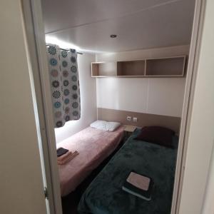 a small bedroom with two beds and a window at Mobilhome 6P 3CH Nature & Sport - Ivry-La-Bataille - Séjour Normandie in Ivry-la-Bataille +4 photos