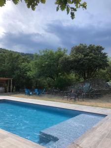 a swimming pool with tables and chairs and trees at Gîte Le Cèdre in Beauchastel +17 photos
