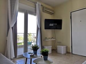 a living room with a couch and a tv on the wall at Almond Apartments in Orfánion