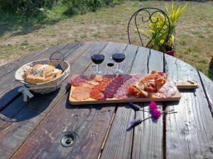 a wooden table with a plate of food and two glasses of wine at MAS BERRUGUES in Bélesta +49 photos