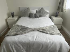 a white bed with a blanket on top of it at Modern newly refurbished 2 bedroom house in Croydon in Croydon