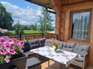 porche con sofá, mesa y flores en Tatra West Farm, en Dzianisz
