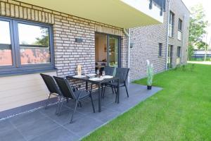 a patio with a table and chairs on a lawn at Luv Exklusive Ferienwohnung mit Sauna & nah am Strand! in Butjadingen OT Tossens