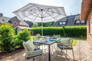 a table and chairs with an umbrella on a patio at Letj Lindguard in Alkersum