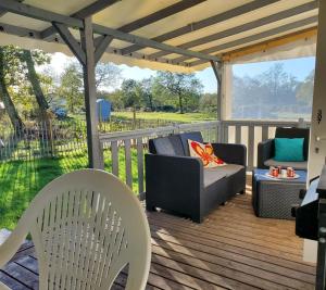 a deck with chairs and a couch and a table at Mobilhome vue sur la lande in Mimizan