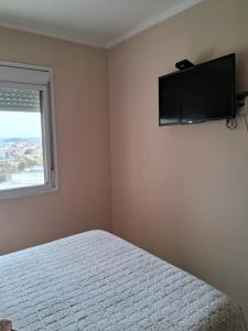 a bedroom with a bed and a flat screen tv on the wall at Apartamento Cond JK Parque Club in Pelotas