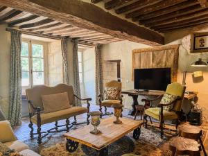 a living room with chairs and a tv and a table at Le manoir de Saint-Ouen avec piscine chauffée intérieure in Saint-ouen-de-la-Cour