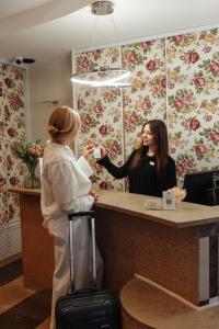 a woman standing at a counter in front of a customer at Hotel Victory Home in Warsaw