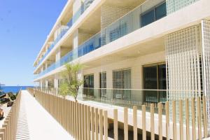 a building with a wooden fence next to the ocean at Beachside 2 BD Apartment | Balcony | AC in Vila Nova de Gaia