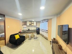 a living room with a black chair and a kitchen at Mini departamento en Cajamarca in Cajamarca