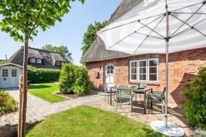 a patio with a table and chairs and an umbrella at Kurnkoomer in Alkersum